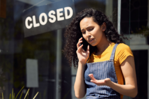 Stock photo of a young female employee talking on a phone outside at work.