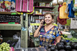 Mature woman retail shop owner at her market store talking in a mobile phone